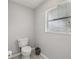 Neutral half bath with updated commode, hardwood style floors, and window at 2251 Evenglow Ave, Spring Hill, FL 34609