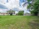 A grassy, expansive backyard featuring lush green space and mature trees at 2414 San Luis Rd, Holiday, FL 34691