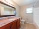 Bathroom with wood cabinets, granite counters, a window, and tile flooring at 2414 San Luis Rd, Holiday, FL 34691