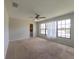Spacious bedroom featuring carpet flooring, neutral walls, a ceiling fan, and a view to the outside at 2414 San Luis Rd, Holiday, FL 34691