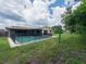 Exterior view of a pool surrounded by a safety fence and a large screened lanai area at 2414 San Luis Rd, Holiday, FL 34691