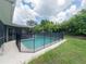 Backyard showcases a sparkling swimming pool with safety fence and lush landscaping at 2414 San Luis Rd, Holiday, FL 34691