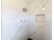 Close up of a modern walk-in shower with marble-style tile walls and black honeycomb floor tiles at 2414 San Luis Rd, Holiday, FL 34691