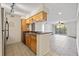 Open kitchen with wood cabinets, tiled floors, and bar seating that opens to the living room and balcony at 2500 Winding Creek Blvd # G106, Clearwater, FL 33761