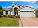 Charming home with lush landscaping, a brick driveway, and a two-car garage at 252 Arbor Woods Cir, Oldsmar, FL 34677