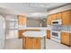 Spacious kitchen with island, white appliances, light wood cabinets, and view into the living room at 252 Arbor Woods Cir, Oldsmar, FL 34677