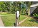 Exterior view of a home's Tesla charging station with lush green lawn, shrubs, and mature shade trees at 25487 Dan Brown Hill Rd, Brooksville, FL 34602
