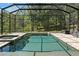 Screened-in pool area complete with a spacious paver deck, hot tub, and views of lush landscaping at 25487 Dan Brown Hill Rd, Brooksville, FL 34602