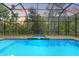 Screened-in pool area complete with a spacious paver deck, hot tub, and views of lush landscaping at 25487 Dan Brown Hill Rd, Brooksville, FL 34602