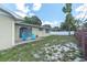 View of the home from the spacious backyard with blue chairs and a white and red brick fence at 2954 Leisure Ct, Dunedin, FL 34698
