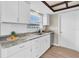 Well-lit kitchen with white cabinets, granite countertops, modern appliances, and stylish flooring at 2954 Leisure Ct, Dunedin, FL 34698