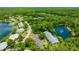 Community aerial view showing manicured landscaping, mature trees, lake, pool, and community tennis court at 3134 Lake Pine Way # F2, Tarpon Springs, FL 34688