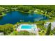 Aerial view of a community featuring a pool, a lake with trees, parking, and well-maintained buildings at 3134 Lake Pine Way # F2, Tarpon Springs, FL 34688