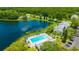 An aerial view of a lakefront community featuring a pool, parking, and well-maintained buildings amid lush greenery at 3134 Lake Pine Way # F2, Tarpon Springs, FL 34688
