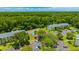 Aerial view of complex featuring a tennis court, a parking lot, and mature trees at 3134 Lake Pine Way # F2, Tarpon Springs, FL 34688