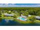 Aerial view of complex featuring a pool, lake, and lush green landscape with many mature trees at 3134 Lake Pine Way # F2, Tarpon Springs, FL 34688