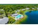 Aerial view of complex featuring a pool, lake, and lush green landscape with sidewalks and parking at 3134 Lake Pine Way # F2, Tarpon Springs, FL 34688
