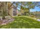 Exterior lake view of the condos with a community bench in the lush grassy yard with mature trees at 3134 Lake Pine Way # F2, Tarpon Springs, FL 34688