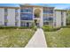Exterior view of the condo buildings showing manicured landscaping and a concrete walkway to the building at 3134 Lake Pine Way # F2, Tarpon Springs, FL 34688