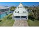 A-frame stilt home with light green siding, black shutters, and covered parking area at ground level at 3363 Poinsettia Dr, Hernando Beach, FL 34607