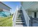 Outdoor stairway with painted steps and white railing, leading to the entrance of the elevated home and the canal view at 3363 Poinsettia Dr, Hernando Beach, FL 34607