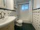 Bathroom with retro tiled walls and dark green floor, along with a shower-tub combo and vanity sink at 3530 Beechwood N Ter, Pinellas Park, FL 33781
