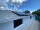 A clean, white house exterior with solar panels installed on the roof, set against a blue sky and clouds at 3530 Beechwood N Ter, Pinellas Park, FL 33781