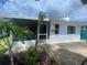 A view of the home's exterior showing the sunroom, plants, siding and a well-manicured lawn at 3530 Beechwood N Ter, Pinellas Park, FL 33781