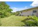 Lush backyard featuring green grass, mature trees, and a covered porch area on a sunny day at 37722 Granada Ave, Dade City, FL 33525