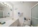 Bright bathroom features a white vanity, mirror with decorative lighting, and a walk-in shower with glass door at 37722 Granada Ave, Dade City, FL 33525