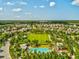 Aerial view of a residential community with a large green space, swimming pools, and mature trees at 3897 Villamore Ln, Odessa, FL 33556