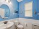 Nautical themed half bathroom with a round mirror and bright blue accent walls at 3897 Villamore Ln, Odessa, FL 33556