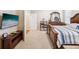 Well-lit bedroom featuring a large bed, a mounted TV, and soft carpet at 3897 Villamore Ln, Odessa, FL 33556
