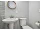 Bathroom featuring a white pedestal sink, round mirror, toilet and light gray walls at 4007 S Renellie Dr, Tampa, FL 33611