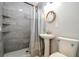 Modern bathroom with pedestal sink, marble tile shower and a round mirror at 4007 S Renellie Dr, Tampa, FL 33611