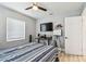 Bedroom featuring ceiling fan, light gray walls, and desk beneath mounted TV at 4007 S Renellie Dr, Tampa, FL 33611