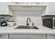 Modern kitchen sink area with white countertops, stylish faucet, and herringbone backsplash at 4007 S Renellie Dr, Tampa, FL 33611