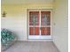 Close-up of a charming front porch with seating area, decorative bird art, and unique double storm doors at 4646 Lacrosse Ct, New Port Richey, FL 34655