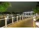 Night view of a lovely lit pier overlooking a lake with fountains, palm trees, and nearby buildings at 4939 Floramar Ter # 203, New Port Richey, FL 34652