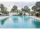 Community outdoor pool featuring lounge chairs, lush greenery, and a fence surrounding the area at 4939 Floramar Ter # 203, New Port Richey, FL 34652