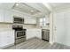 Well-lit kitchen featuring stainless steel appliances, white cabinets, and a convenient entrance door at 4939 Floramar Ter # 812, New Port Richey, FL 34652