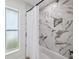 Close-up of marble tiled shower and tub combo with white shower curtain, next to frosted window at 5348 Lawrence Ln, New Port Richey, FL 34652