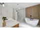 Modern bathroom featuring double vanity, marble shower, and freestanding tub with wood-paneled accent wall at 5348 Lawrence Ln, New Port Richey, FL 34652