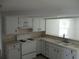Well-lit kitchen features white cabinets and a sink overlooking the adjacent room at 6030 17Th St, Zephyrhills, FL 33542