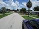 Residential street featuring single-Gathering homes, manicured lawns, and mature trees under a sunny sky at 6030 17Th St, Zephyrhills, FL 33542