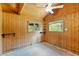 Bedroom featuring wood-paneled walls, a ceiling fan, and windows at 6410 Amelia Ln, Dade City, FL 33523