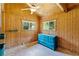 Charming bedroom featuring wood-paneled walls, natural light, and a stylish blue dresser, creating a serene retreat at 6410 Amelia Ln, Dade City, FL 33523