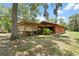 Exterior view of a charming orange house with a screened-in porch and lush greenery at 6410 Amelia Ln, Dade City, FL 33523
