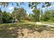 Exterior view of an orange house surrounded by a large, grassy yard and mature trees at 6410 Amelia Ln, Dade City, FL 33523
