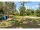 Exterior view of a charming orange house with large trees and greenery at 6410 Amelia Ln, Dade City, FL 33523